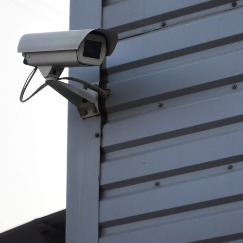 White surveillance camera built into the metal wall of the office building